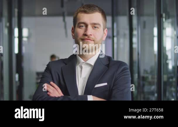 Confident young businessman in a suit standing in a modern office ...