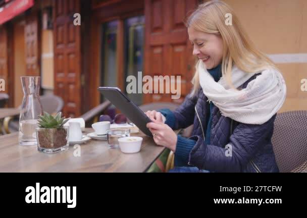 A young woman enjoys her time at a caf, using a tablet while sipping ...