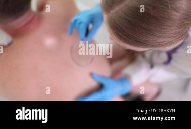 Woman dermatologist examines acne on back of patient. Doctor uses ...