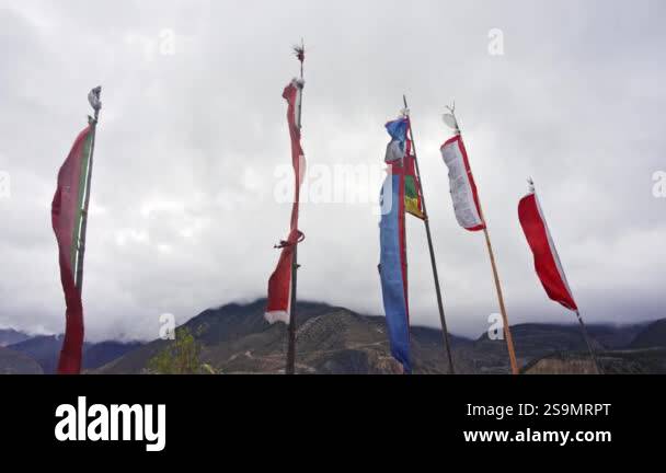 Colorful prayer flags wave in the wind against a dramatic cloudy sky ...