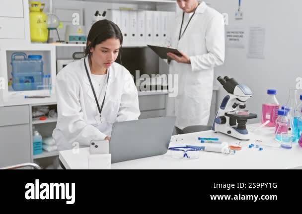 A man and woman in white lab coats working together in a science ...