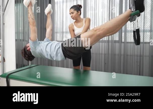 Healthy client practicing inverted leg raise on Pilates Cadillac under ...