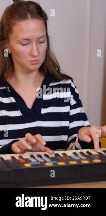 Female musician practises playing keyboard by recording intricate ...
