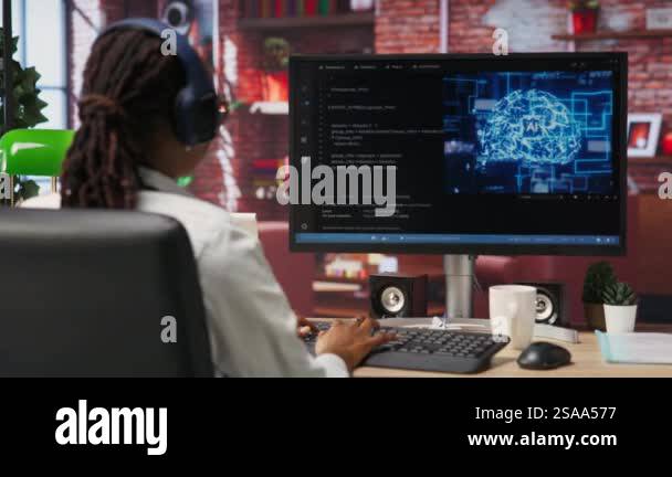 Software developer wearing headphones using computer at home for ...
