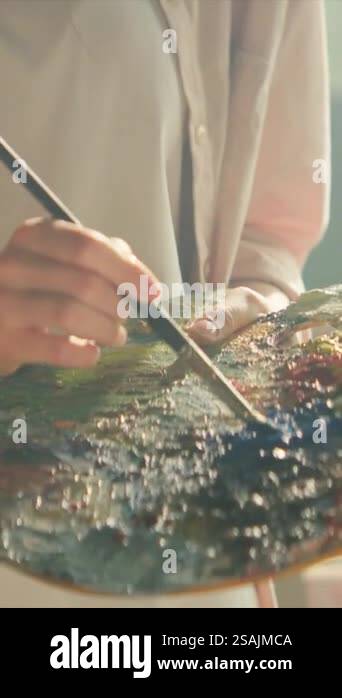 At sunlight young artist painting with oil paint picture on canvas hold ...