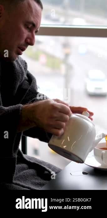 Teapot Computer teapot cup laptop white near window Adult man at work in a gray T-shirt ...