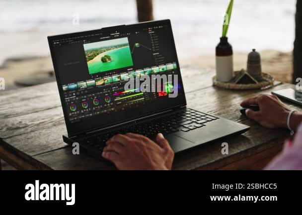 Pro color grading footage of ocean. Male video editor works on laptop ...
