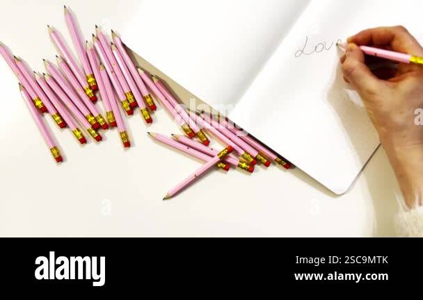 A girl holds a pencil in her hand and writes text 'Love yourself first ...