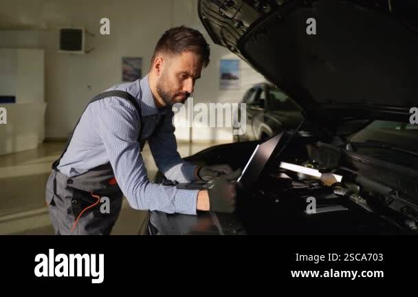 A professional auto mechanic in a workshop carefully examines car
