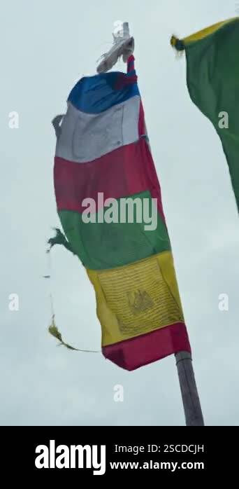 Colorful prayer flags fluttering in the wind, set against a blue sky ...