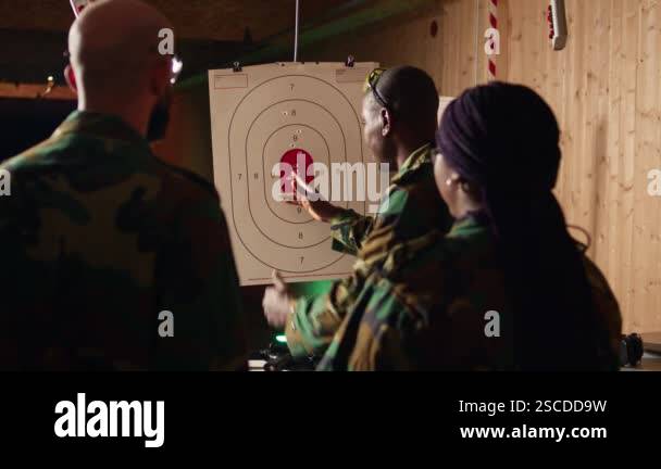 Army commander teaching recruits in shooting gallery how to shoot paper ...