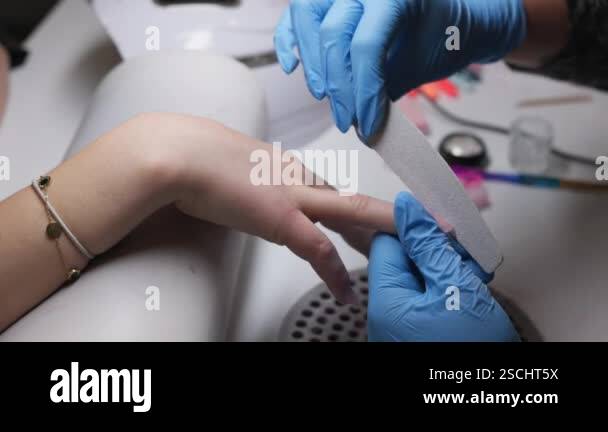 A skilled and professional nail technician expertly shaping and ...