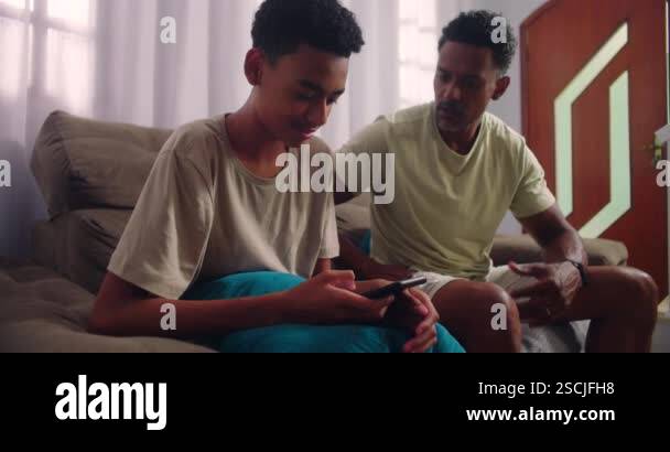 Image showcasing Father taking teenage son's phone, demanding eye contact to address ...