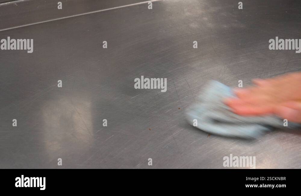 A man cleans a metallic kitchen counter with a rag - closeup Stock ...