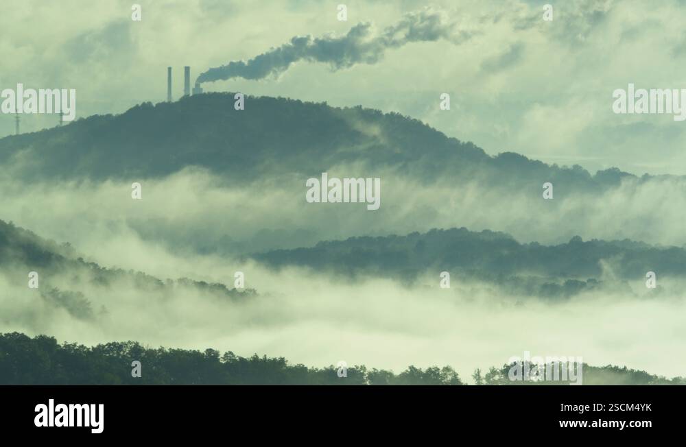 Power plant chimney releasing smoke on the mountain top at sunrise ...