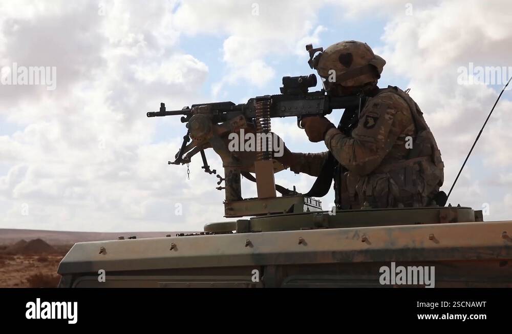 Soldier firing machine gun from armoured vehicle during exercise ...