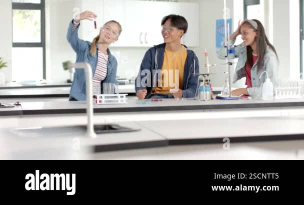 In high school laboratory, teenagers conducting science experiment with ...
