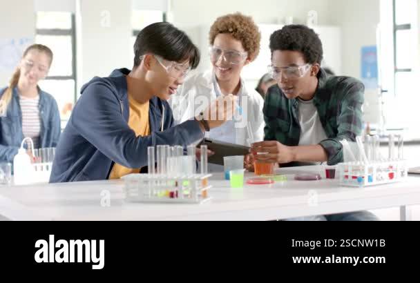 In high school, teenagers conducting science experiment with test tubes ...