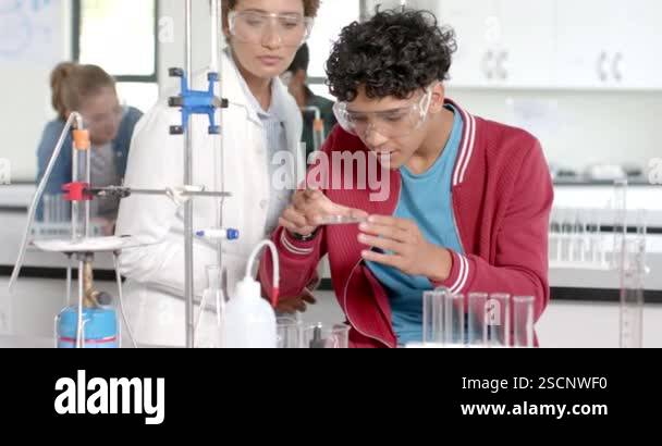In high school, teenager conducting science experiment with teacher in ...