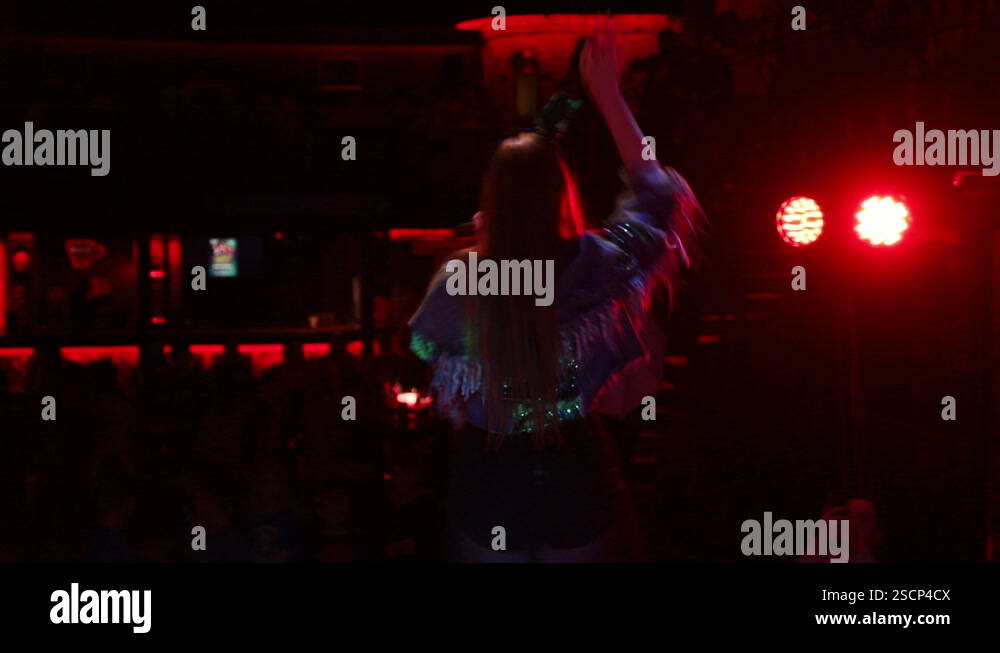 On Stage Back View Rapper Girl who sings and dances on stage, Back view of singer. Light and ...
