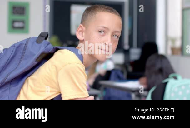Biracial boy smiles in a classroom at school, with copy space. He's ...