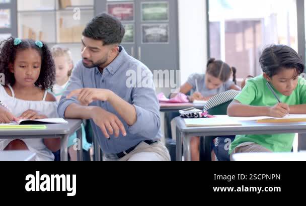 Young teacher assists a biracial girl in a classroom setting at school ...