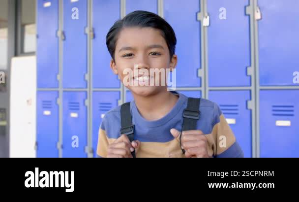 Biracial boy smiles in front of school lockers. He exudes confidence ...