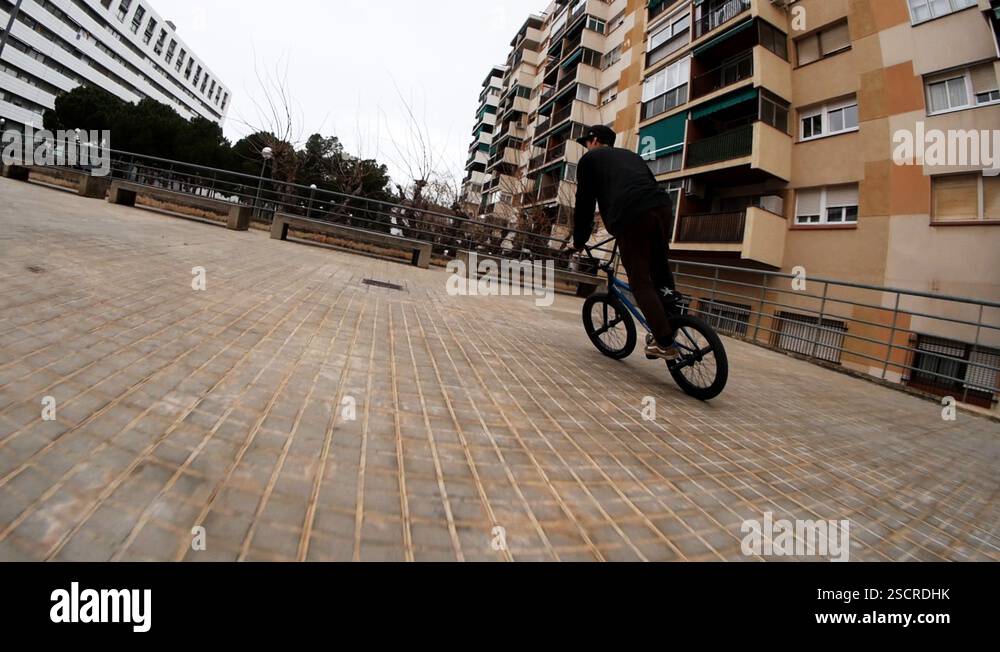 Young man bmx rider rides in street on and jumps on benches and ...