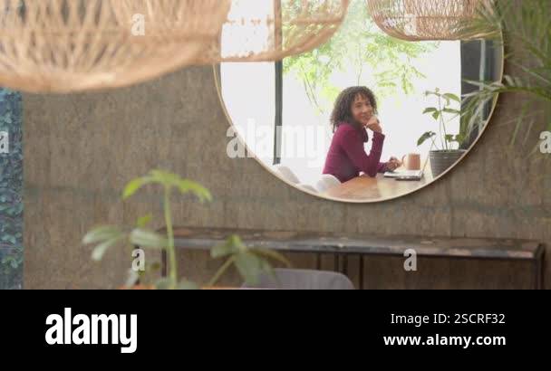 Working from home, woman using laptop at table with potted plant ...