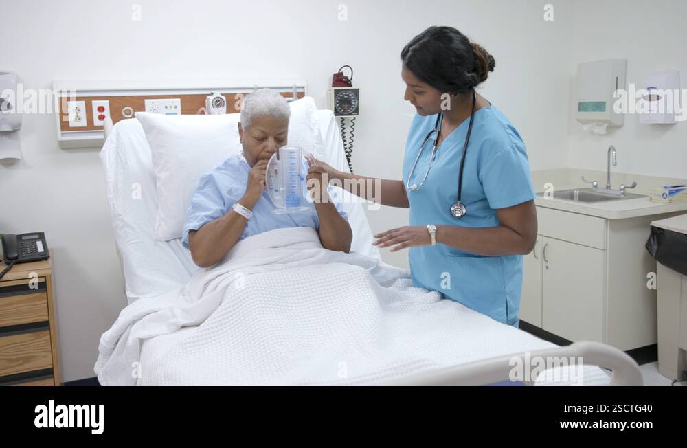Nurse helps female patient with spirometer in hospital patient room ...