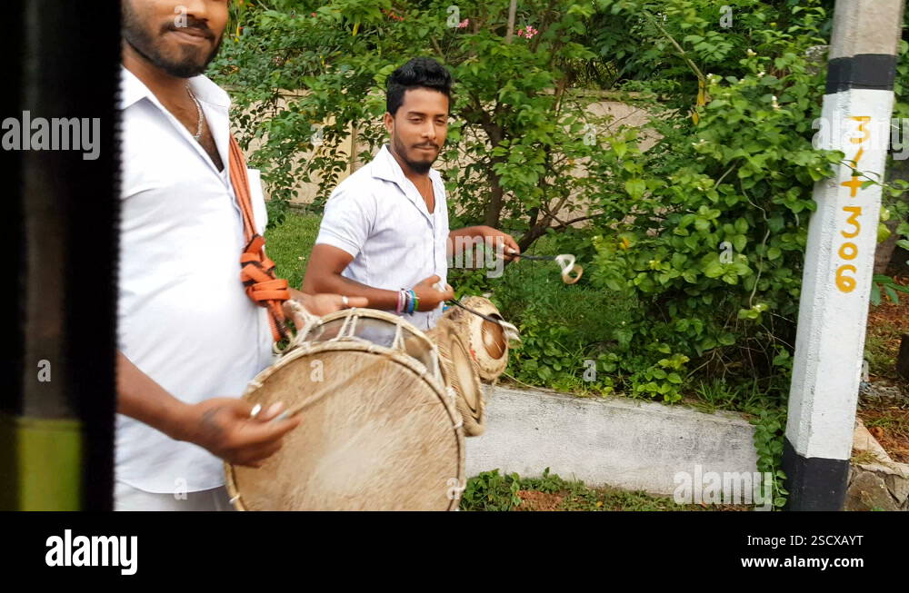 Three local men walk along the street and play traditional musical ...