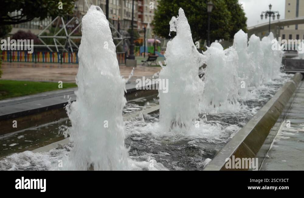 Foamy streams of water rise and fall. Alley of fountains in a city park ...