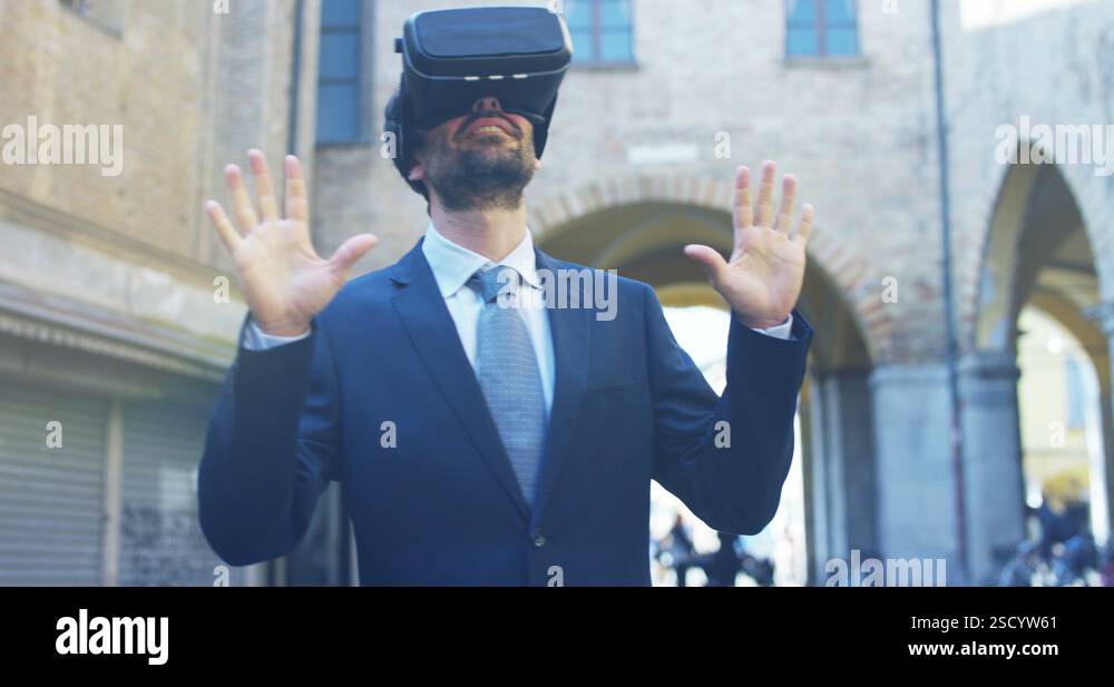 A businessman in a suit is using augmented reality vr glasses in a city ...