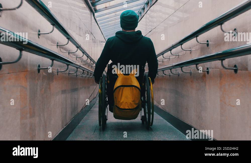 Disabled man in wheelchair getting down the long special ramp in the ...