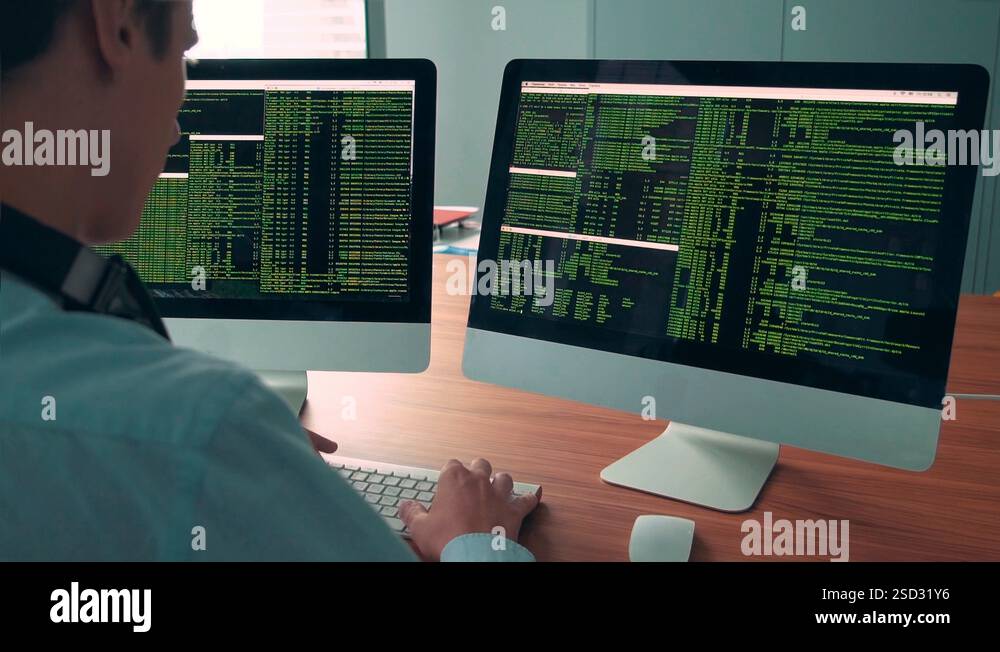 Male hacker in a hood works on a computer with maps and data on display ...