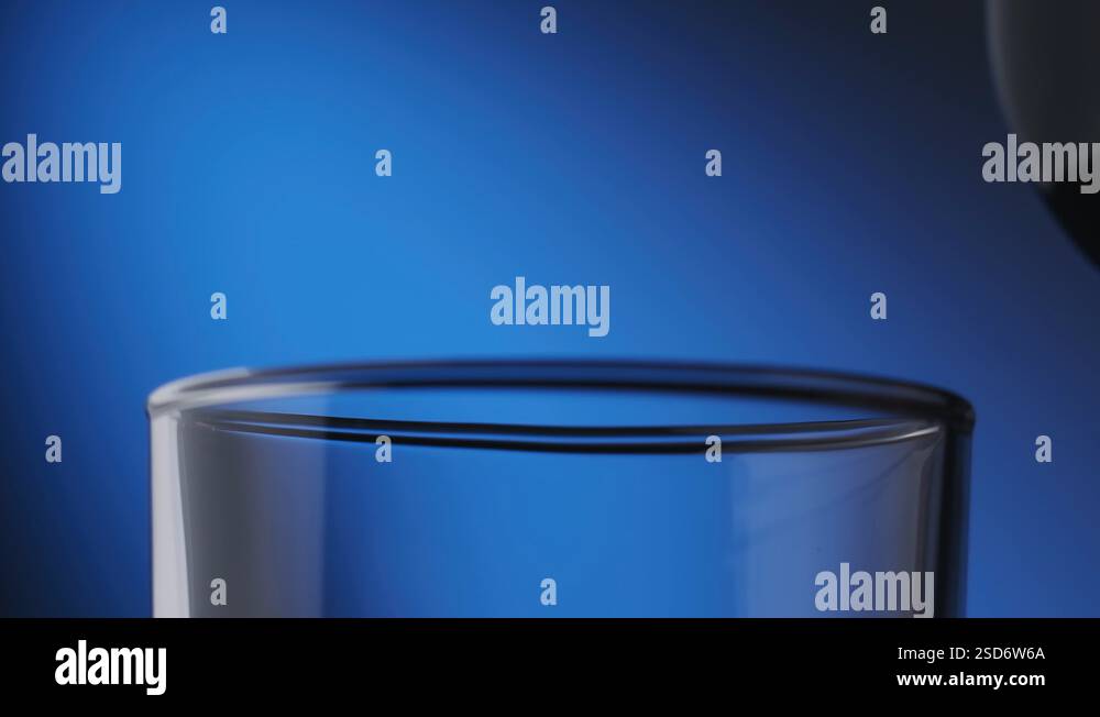 Whiskey poured in glass from bottle at blue background. Pouring bourbon ... Whiskey poured in glass from bottle at blue background. Pouring bourbon ...