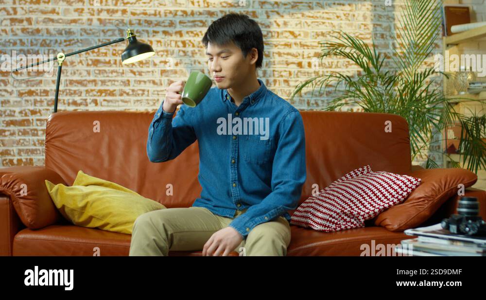 Handsome Asian male model in blue shirt drinking coffee while sitting ...