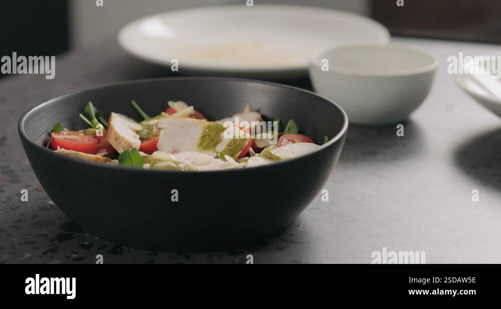 Slow motion eat salad with chicken, arugula and tomatoes in black bowl ...