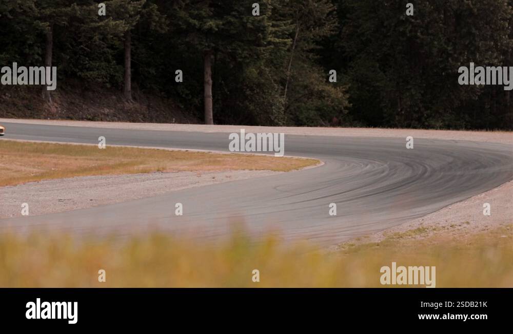 Telephoto of Porsche race car turning corner at high speed. Slow motion ...