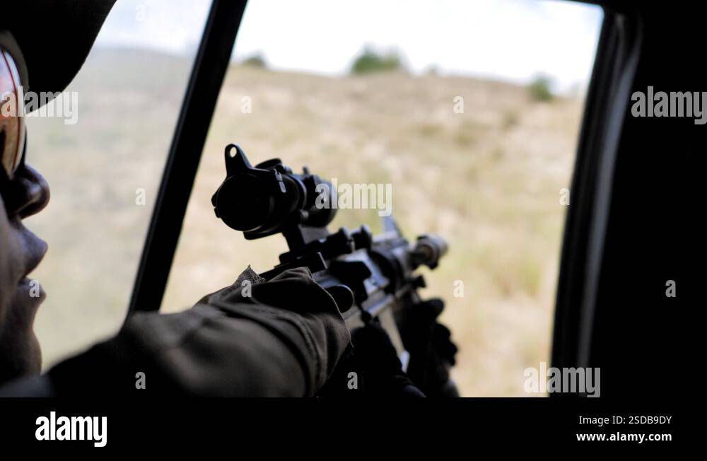 Airsoft. Soldier rides in a car and holds a machine gun, ready to shoot ...