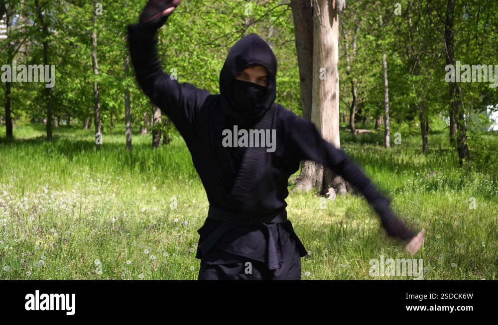 Japanese ninja in a black robe is training in the forest Portrait of a ...