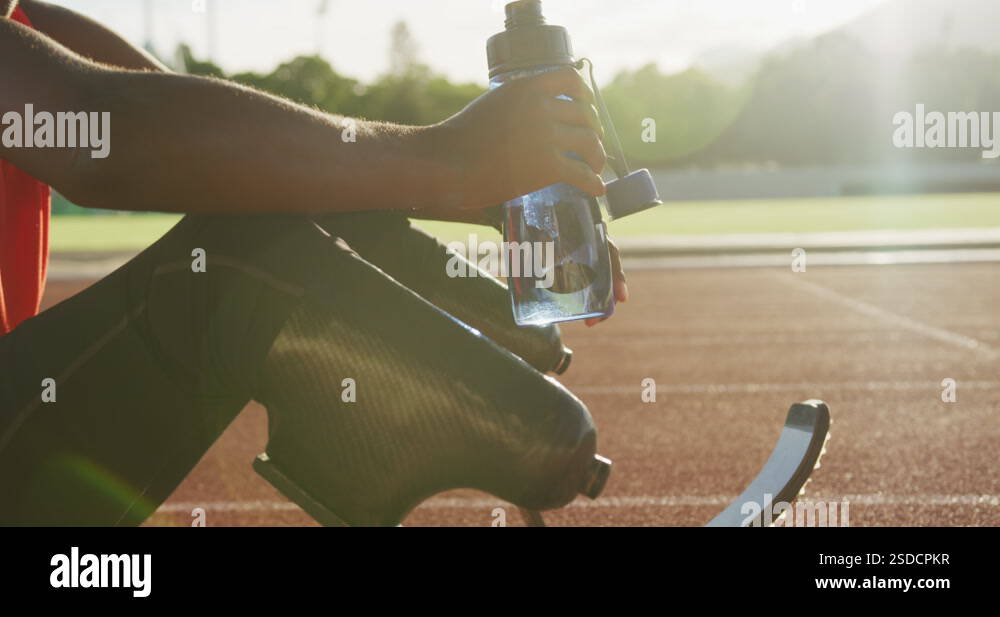 Disabled mixed race man with prosthetic legs sitting on racing track ...