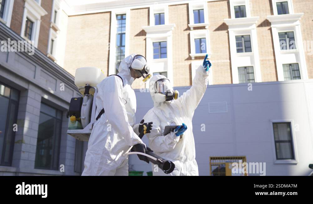 Brave cleaning service workers in biosecurity suit, mask and gloves ...