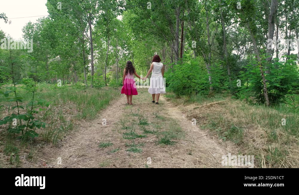 Couple of sisters walking back to back to drone flight on summer forest ...