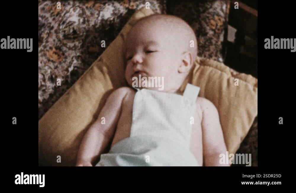 1950s: Infant resting on sofa is prodded and tickled by grandmother's ...