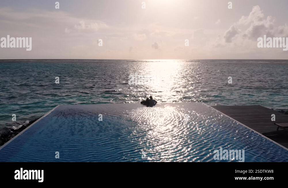 Love couple silhouette on the edge of infinity pool in sunset. Luxury ...