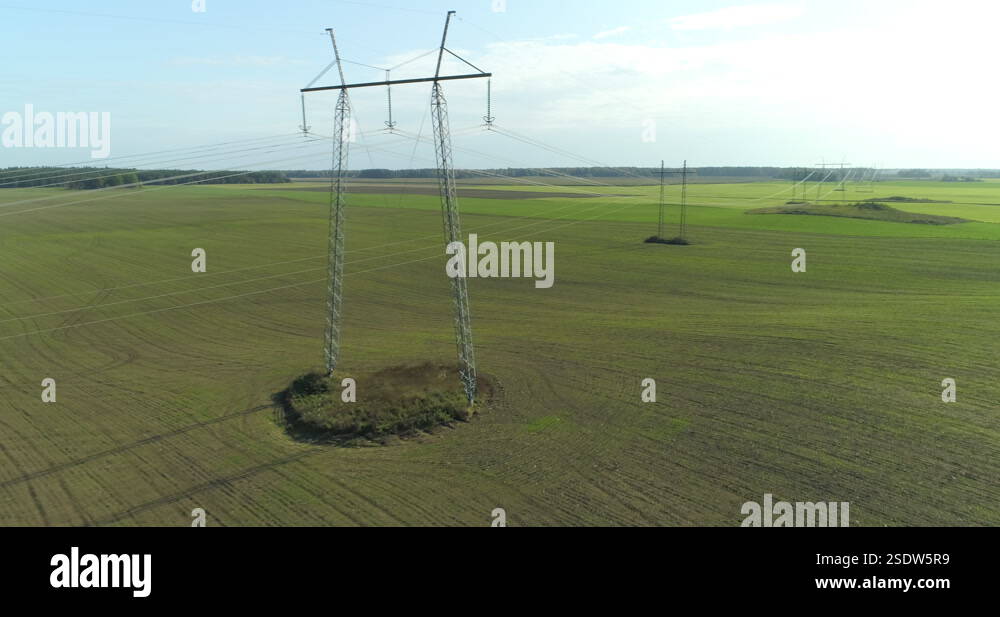 High voltage electricity power lines and pylons in green field aerial ...