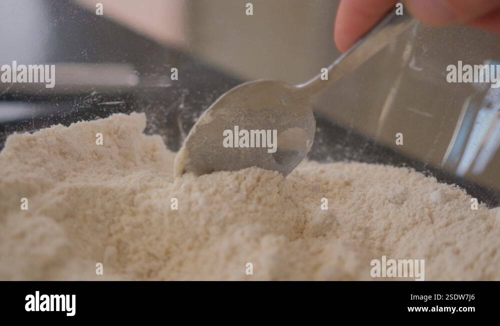 Slow motion following a spoon in a bowl of flour while baking Stock ...