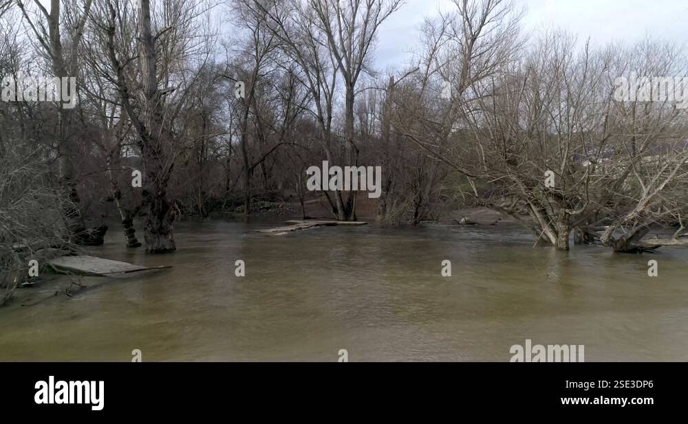 Flying over a river overflowing from a storm with a drone in winter in ...