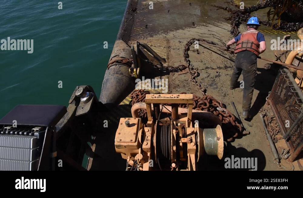 U.S. Coast Guard engineer pushing chain across deck of Cutter Marcus ...